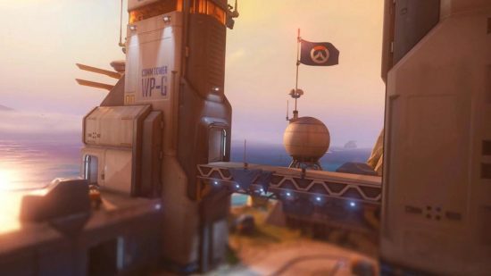 Um mapa de Overwatch 2 mostrando uma cena mostrando um edifício militar na costa ao pôr do sol.