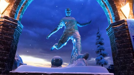 FIFA 23 Volta: uma grande estátua de um jogador de futebol masculino, braços cruzados, perna para trás, lida para chutar uma bola, toda em prata, contra um céu azul escuro entre duas tochas de pedra, iluminadas.