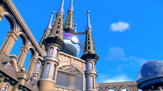 Um edifício com vários pináculos saindo do topo, no meio do qual está uma grande Pokébola.  Parece um pouco com a Sagrada Família.  O céu está azul, com apenas uma nuvem à vista, em uma captura de tela de Pokemon Scarlet and Violet.