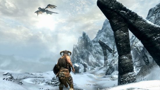 Dragão de Skyrim: Um dragão voa em um céu invernal acima de uma grande passagem de montanha na qual um soldado com capacete com chifres está em uma captura de tela de Skyrim.